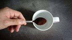 a person holding a spoon with some food inside of it on a black counter top