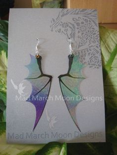 a pair of dragon earrings on top of a card