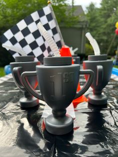 two cups sitting on top of a car with flags in the backgroung