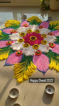 a colorful flower design on the ground with candles in front of it and an inscription that reads happy diwali 2012