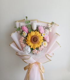 a bouquet of flowers is wrapped in pink and white paper with the word congratulations written on it