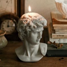 a candle that is sitting on top of a table next to books and a clock