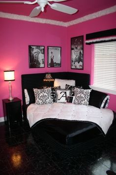 a bedroom with pink walls, black and white bedding and pictures on the wall