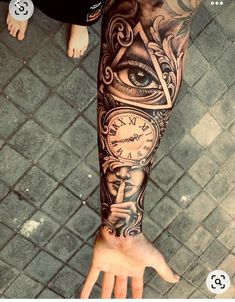 a person's arm with an eye and clock tattoo on it, next to a brick floor