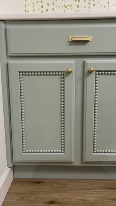 a gray cabinet with gold handles and knobs