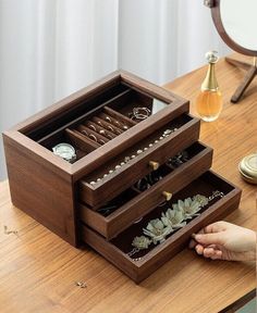 a person holding their hand in front of an open drawer on a table with other items