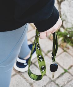 a person holding onto a green lanyard with a pair of keys attached to it