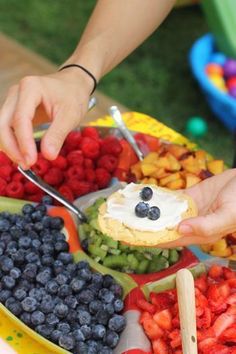 a person is cutting up some food on a plate with berries and blueberries in it