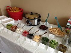 an assortment of food is displayed on a white tablecloth with red buckets and other items