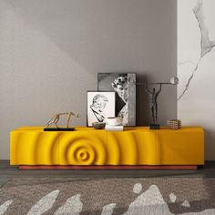 a yellow cabinet with pictures on it in a living room next to a rug and wall