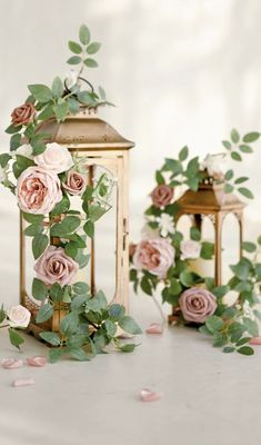 some pink flowers and green leaves on a white table with a small light fixture in the background