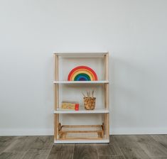 a white shelf with a rainbow painted on the top and a wicker basket next to it