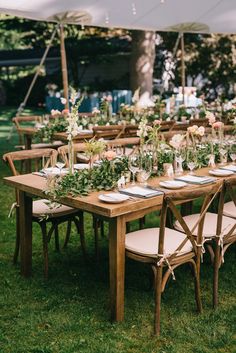 an outdoor table set up with flowers and greenery