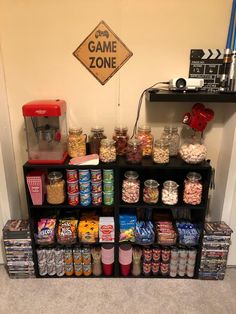 a shelf filled with candy and snacks next to a game zone sign