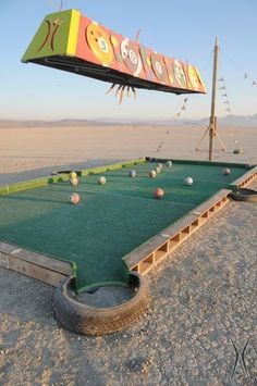 an outdoor game area in the desert with balls on it and a sign above it