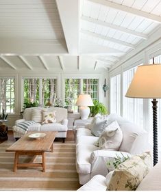 a living room filled with white furniture and lots of windows