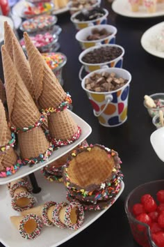 a table topped with lots of desserts and ice cream cones covered in sprinkles