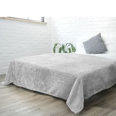 a bed sitting on top of a wooden floor next to a white brick wall in a bedroom