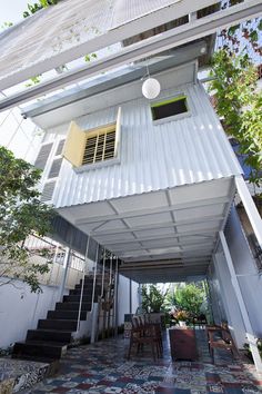 the house is white and has stairs leading up to it's second floor area