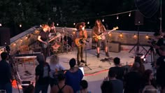 a group of people standing on top of a stage playing guitars and singing into microphones