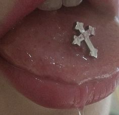 a woman's tongue with a cross on it and water dripping from her mouth