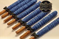 several blue and brown pastry sticks are lined up on a white surface with a black ribbon around them