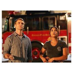 a man and woman standing in front of a fire truck