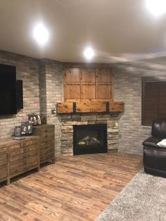 a living room with a fireplace and tv mounted on the brick wall, along with wooden dressers