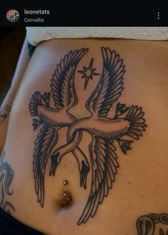 a woman's stomach with a bird tattoo on it and a cross in the middle