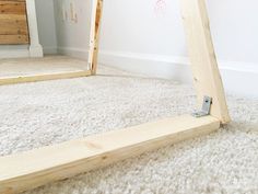 a wooden frame sitting on the floor in front of a mirror