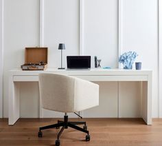 a white desk with a laptop computer on top of it and a lamp next to it