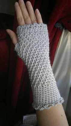 a woman's hand with a knitted arm warmer over her left wrist, on top of a couch