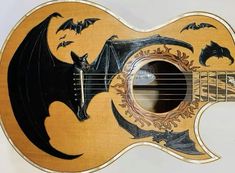 an acoustic guitar with bats painted on it