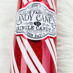 a candy cane bottle with red and white stripes on the top is sitting on a fluffy surface