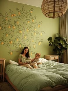 a woman sitting on top of a bed next to a child in front of a tree