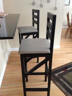 two black and white chairs sitting in front of a counter with a rug on the floor