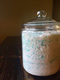 a glass jar filled with white and blue sprinkles on top of a wooden table