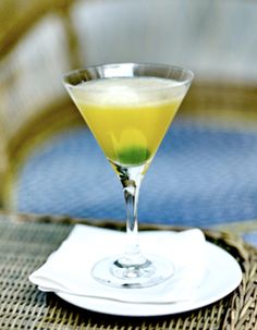 a glass filled with yellow liquid sitting on top of a white plate next to a blue table cloth