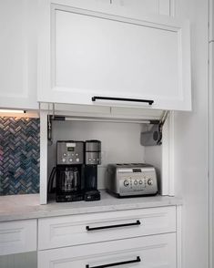 there is a toaster and coffee maker on the counter in this small kitchen with white cabinets