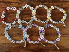 four bracelets with flowers on them sitting on top of a wooden table next to each other