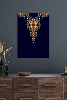 an ornate gold and blue painting on a wall next to a wooden chest of drawers