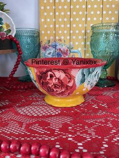 a red and yellow bowl sitting on top of a table next to glass vases