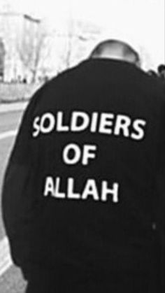 two men standing next to each other on the side of a road wearing jackets that say soldiers of allah