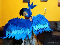 a child is standing in front of a large blue bird made out of construction paper