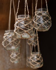 several glass jars hanging from rope with water in them