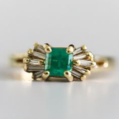 Vintage Ladies 14 Karat Yellow Gold Diamond And Natural Emerald Ring Containing One Square Cut Emerald Measuring 4.65 X 4.59 And Weighing .70 Carats The Emerald Is Described As Light Color And Included With Good Cut And Polish. The Emerald Has A Large Chip On The Girdle Which Extends Into The Crown. Prong Set On Each Side Of The Emerald Are Five Tapered Baguette Shaped Diamonds. Total Weight Of The Ten Tapered Baguettes Is .26 Carats. Diamonds Are Graded H-I In Color And Vs Clarity. Overal Weigh Emerald Cocktail Ring, Emerald Cocktail, Natural Emerald Rings, Square Cut, Natural Emerald, Emerald Ring, Cocktail Rings, Womens Jewelry Rings, Prong Setting