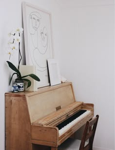 an old piano sits in the corner of a room next to a vase with flowers