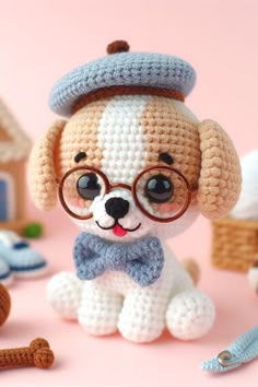 a crocheted dog with glasses and a bow tie sitting in front of toys