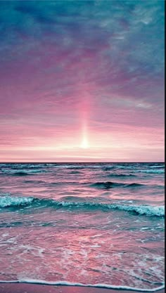 the sun is setting over the ocean with waves coming in to shore and pink sky