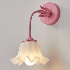 a pink wall light mounted on the side of a white wall next to a lamp